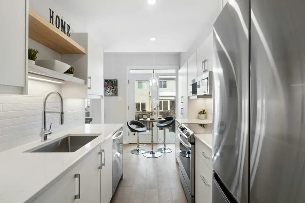 After: A bright, remodeled kitchen with an improved layout. The sink, stove, and fridge now form an open work triangle with ample counter space between each zone. An island adds prep area and seating without disrupting the workflow.